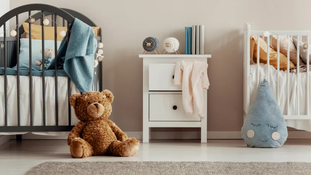 Aufgeräumtes Kinderzimmer mit Teddybär, Kommode und zwei Kinderbetten – steht für funktionale Ordnung im Familienalltag