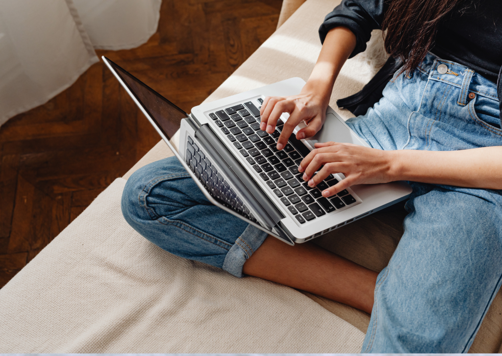 Frau arbeitet im Schneidersitz am Laptop – Online-Ordnungscoaching bequem von zu Hause